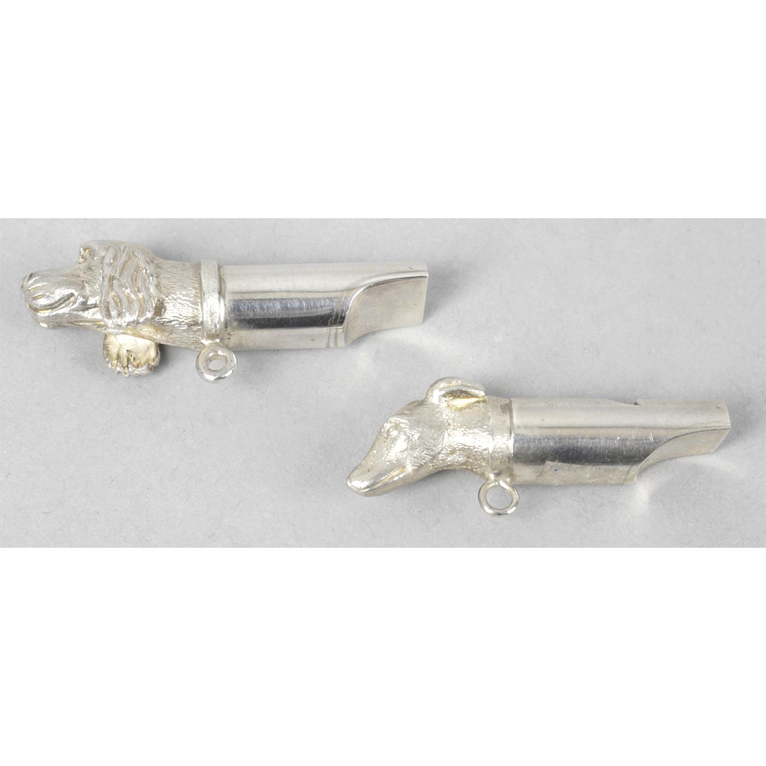 A pair of small silver whistles modelled as dogs' heads, together with a silver rattle and two