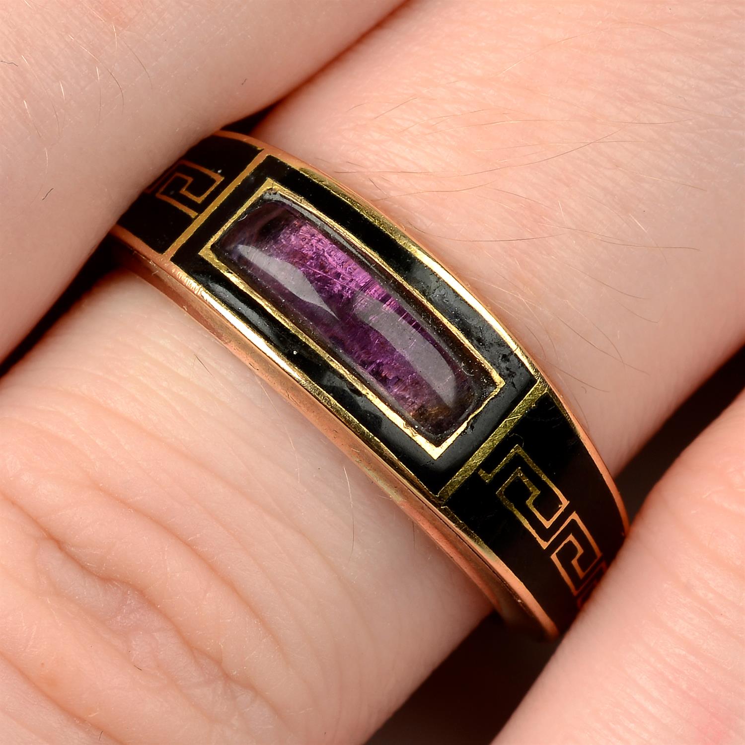 A late Georgian 9ct gold, Greek-key black enamel and foil back amethyst tapered mourning ring.