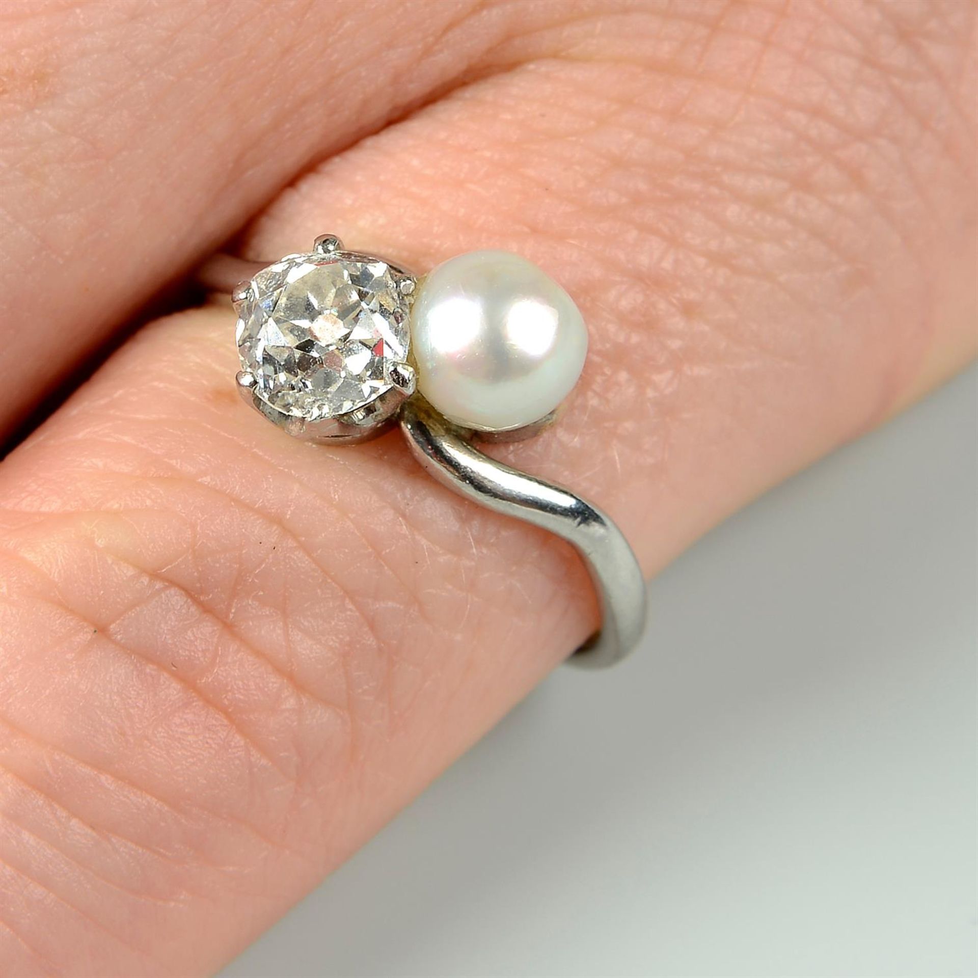 A mid 20th century platinum, old-cut diamond and cultured pearl crossover ring.