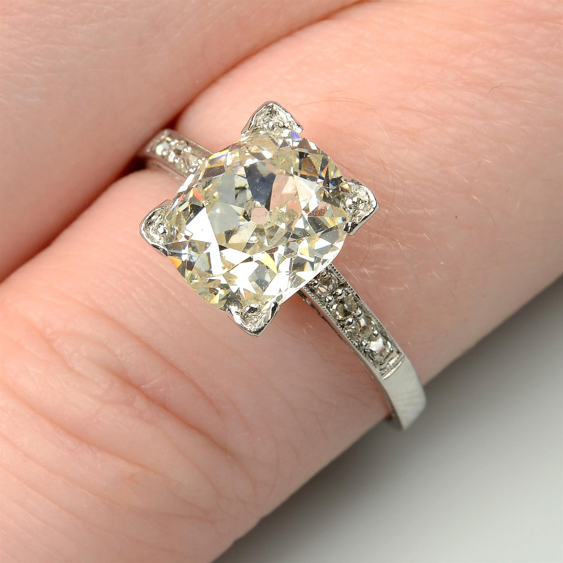 An oval-shape old-cut diamond single-stone ring, with diamond line shoulders.