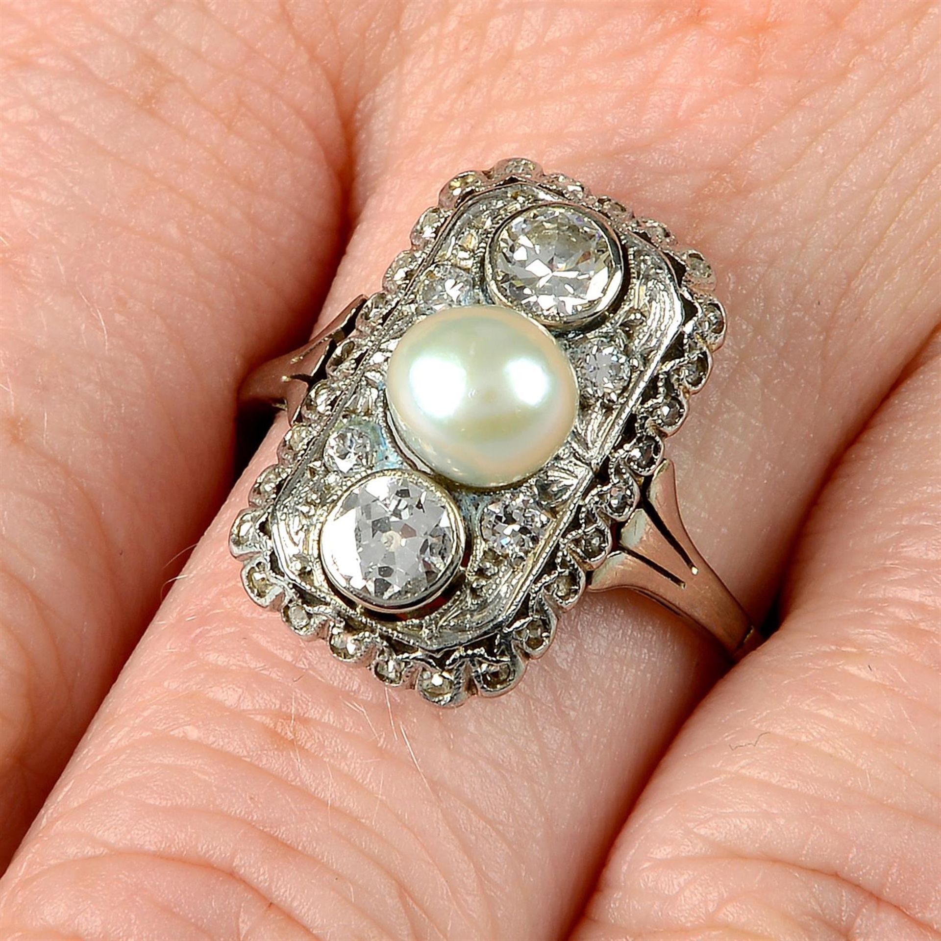 A circular-cut diamond and pearl ring.