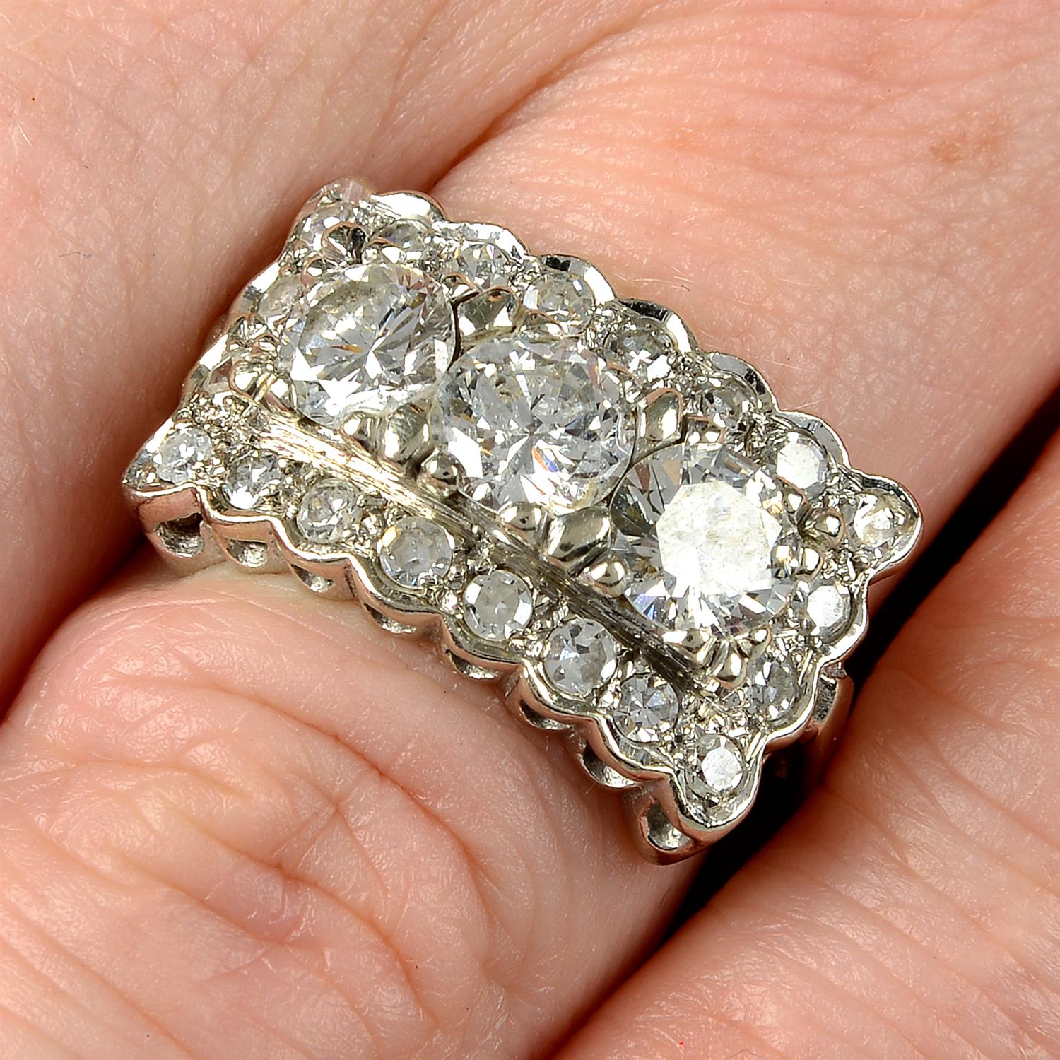 A brilliant-cut diamond three-stone ring, with single-cut diamond shared surround.