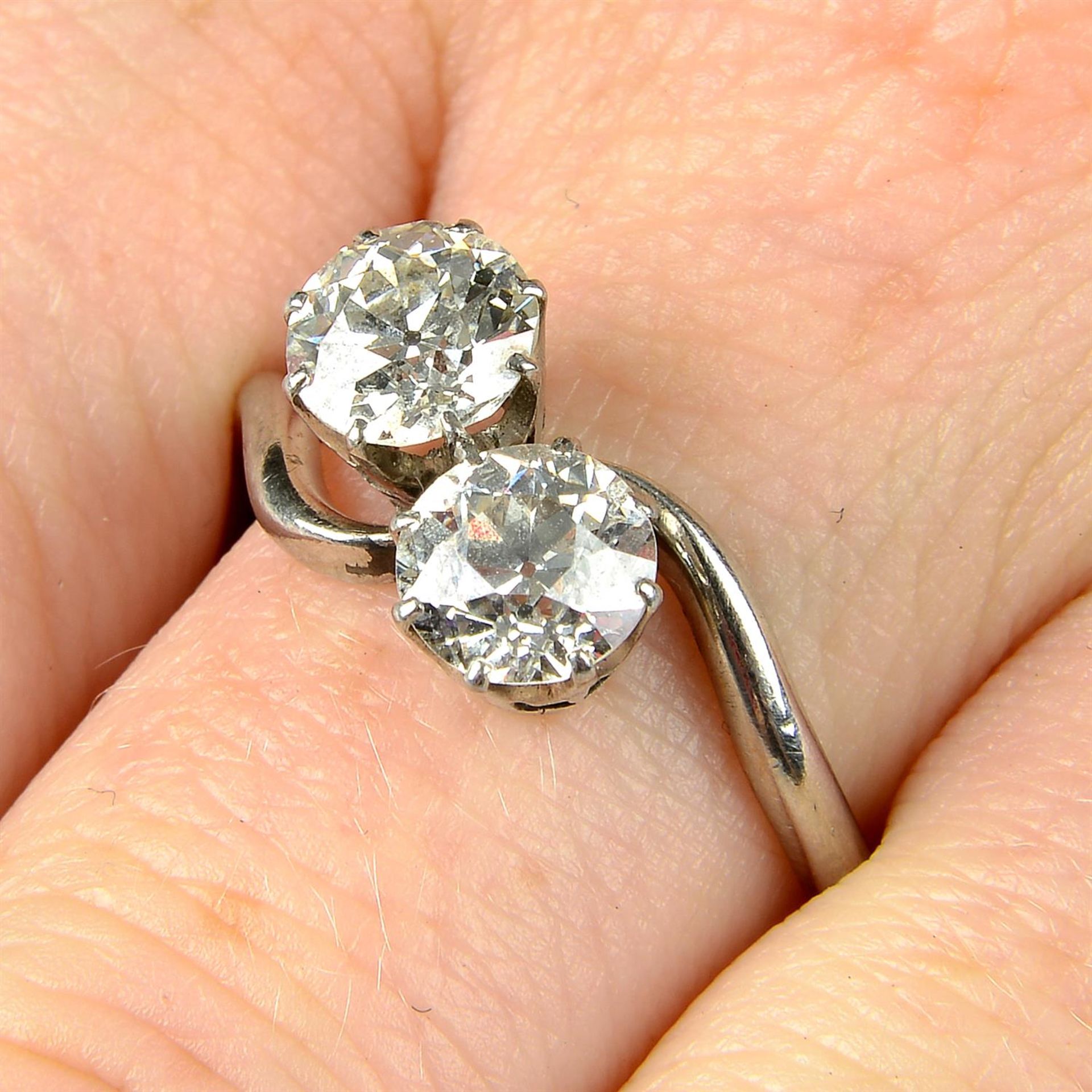 A mid 20th century platinum old-cut diamond two-stone crossover ring.