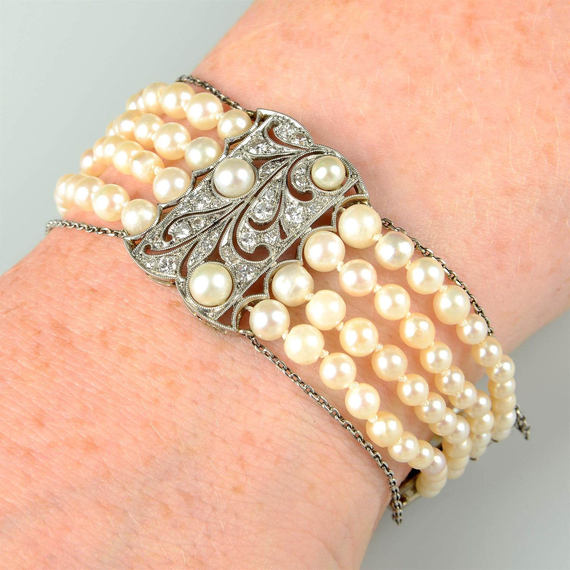 An Art Deco platinum and gold, graduated pearl multi-strand bracelet, with vari-cut diamond and