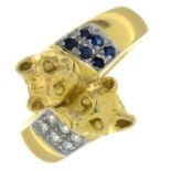 A cubic zirconia and sapphire crossover ring, with cat mask terminals.