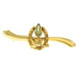 A peridot bar brooch, designed to depict a flower and a horseshoe.