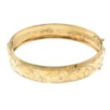 A 1970s 9ct gold bangle, with scrolling foliate motif.