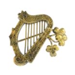 An 18ct gold brooch, designed as a harp and shamrock leaves.