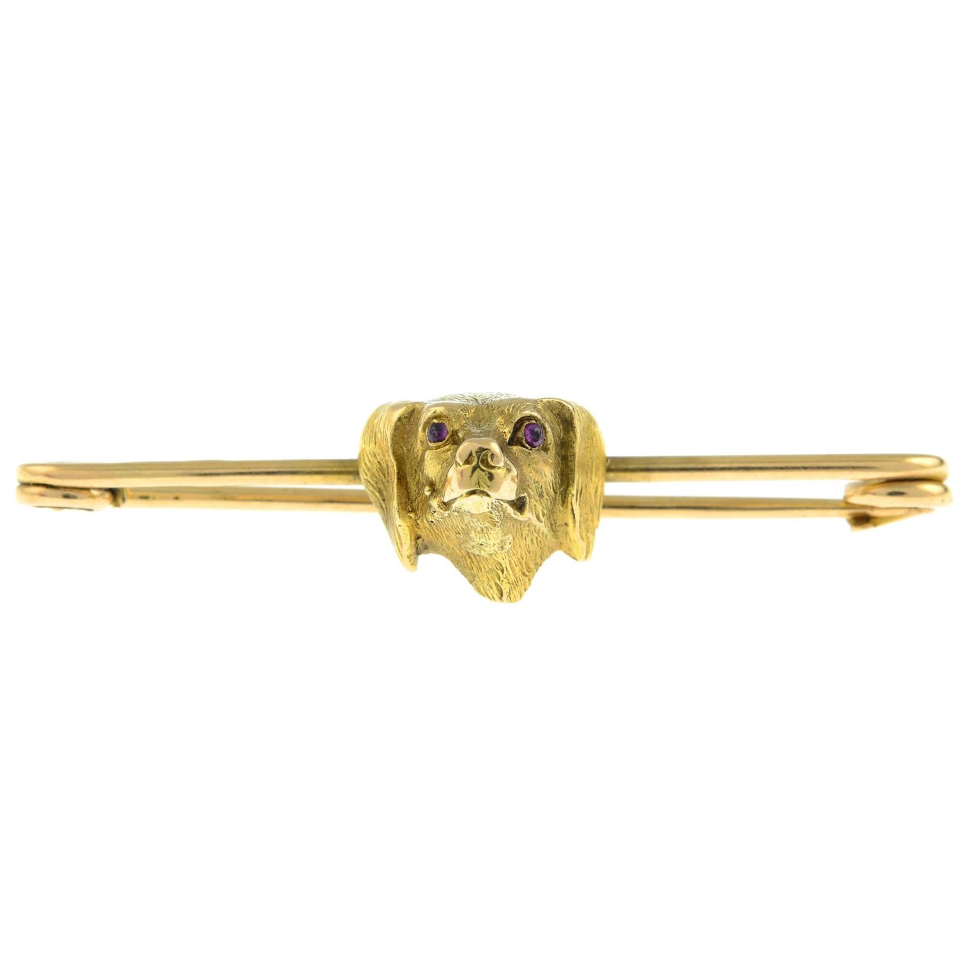 An early 20th century 15ct gold bar brooch of a dog with garnet eyes.