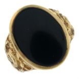 A 9ct gold onyx signet ring with floral shoulders.
