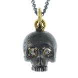 An 18ct gold oxidised pendant of a skull with rose-cut diamond eyes.