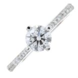 A brilliant-cut diamond single-stone ring, with pave-set diamond shoulders.