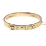 A 9ct gold hinge bangle designed as a buckle with engraved foliate pattern.