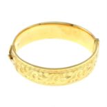 A 9ct gold engraved hinged bangle.