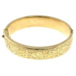 A 1970s 9ct gold foliate bangle, hinged to the plain reverse.