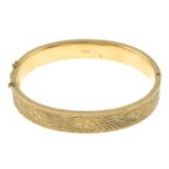 A 9ct gold hinged bangle, with engraved foliate motif.