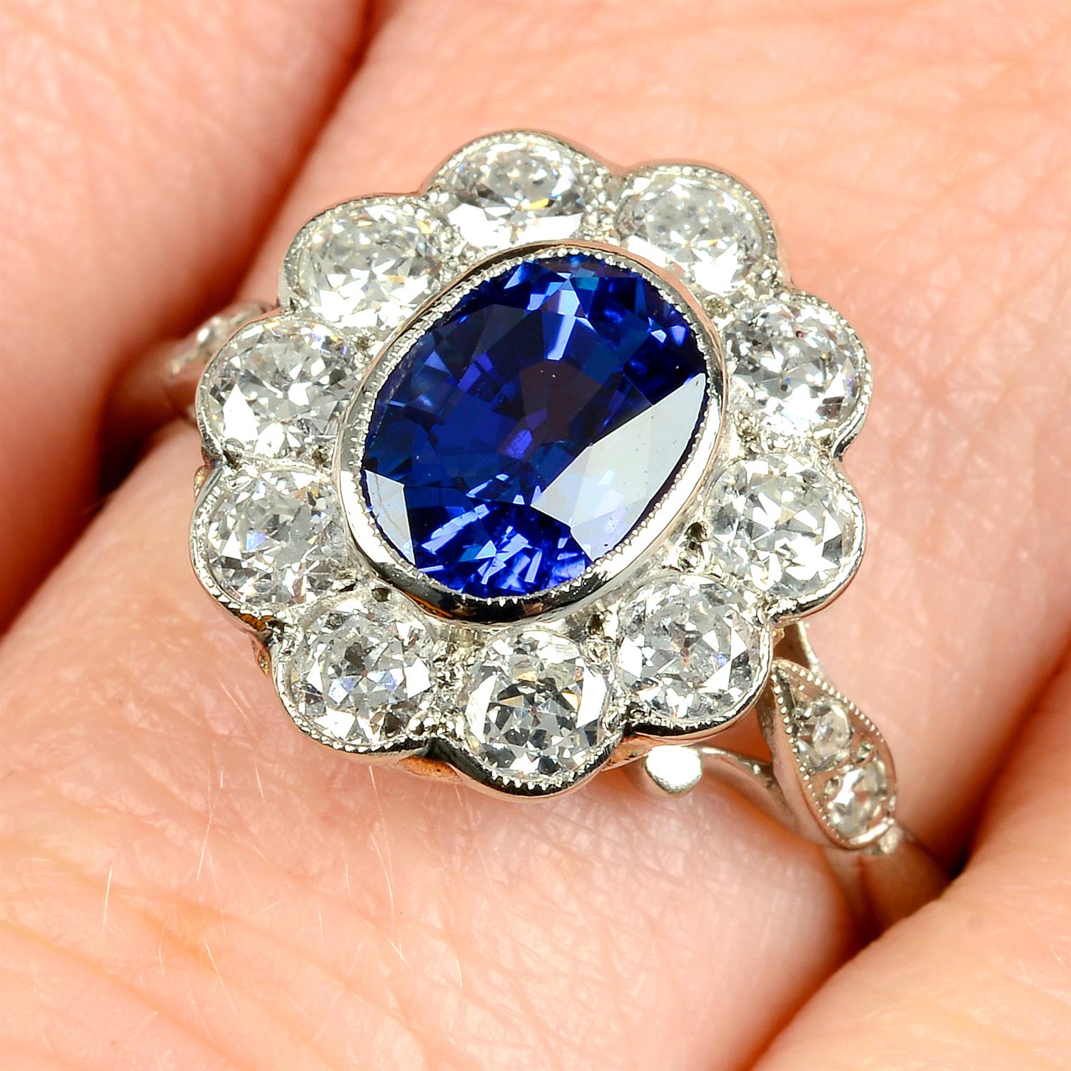 A platinum sapphire and old-cut diamond floral cluster ring.