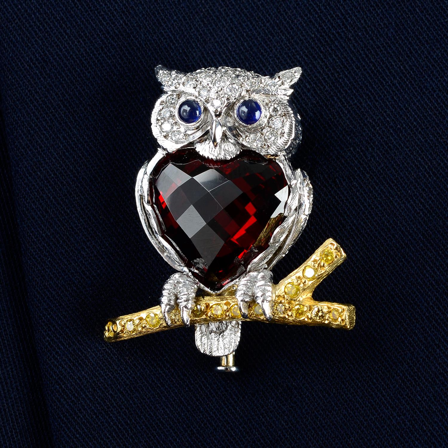 An 18ct gold diamond and garnet owl brooch, with sapphire eyes, perched on a 'yellow' diamond