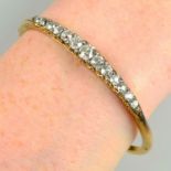 An early 20th century 18ct gold graduated old-cut diamond hinged bangle, with diamond point spacers.