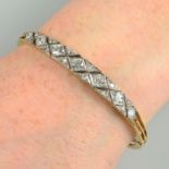 An early 20th century gold, vari-cut diamond pierced lattice, hinged bangle.