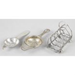 A four bar silver toast rack and two silver tea strainers. (3).