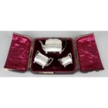 A late Victorian silver three piece bachelor tea set, in fitted case.