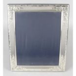A large silver mounted rectangular photograph frame with floral scroll border.