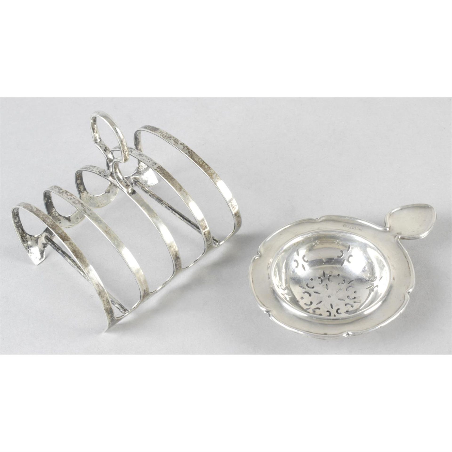 A George V silver five bar toast rack, together with a silver tea strainer. (2).