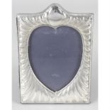 A modern silver mounted photograph frame with heart shape aperture.