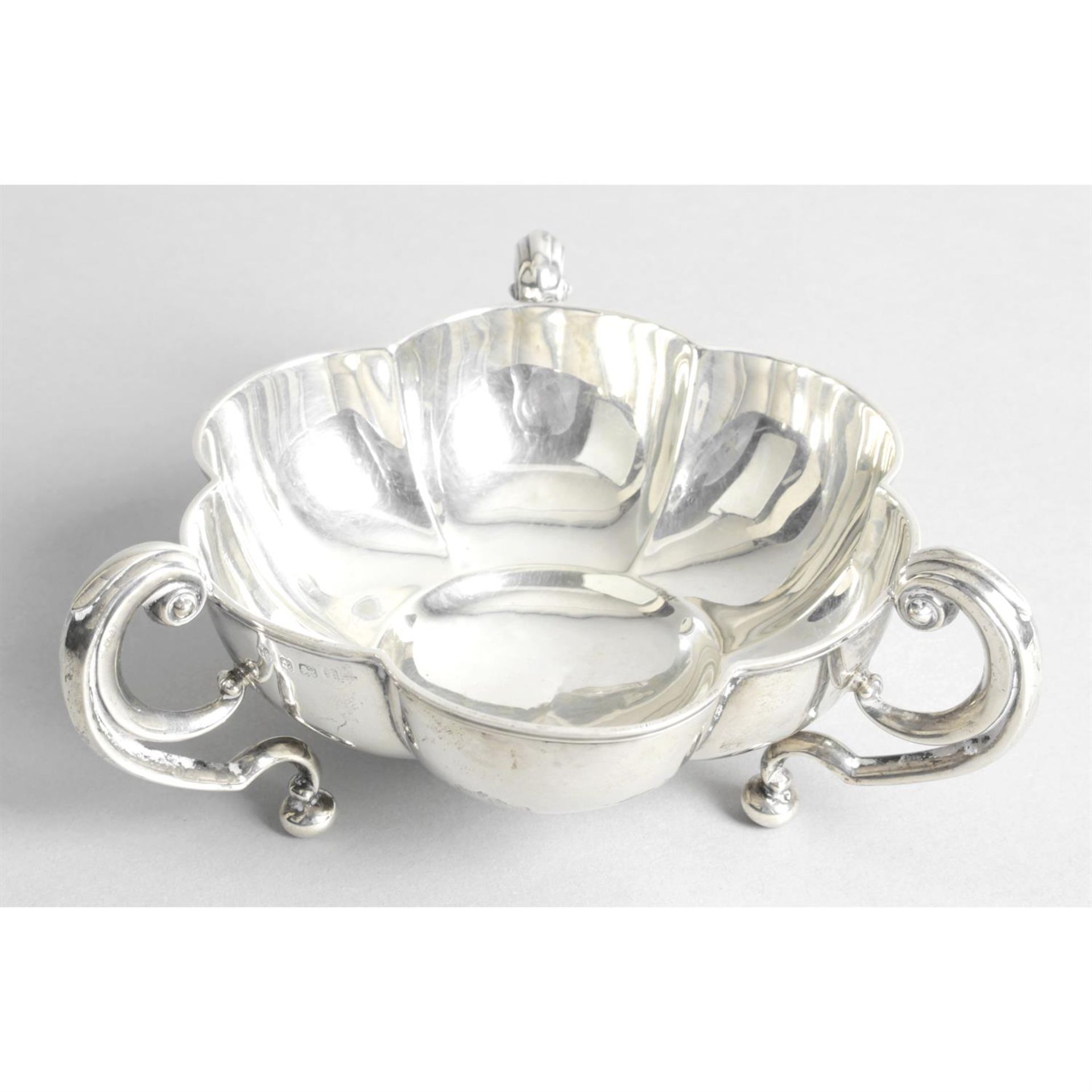 A small Edwardian silver bowl of lobed outline and three handles.