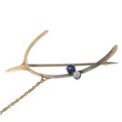 A wishing bone brooch, with sapphire and diamond accents.