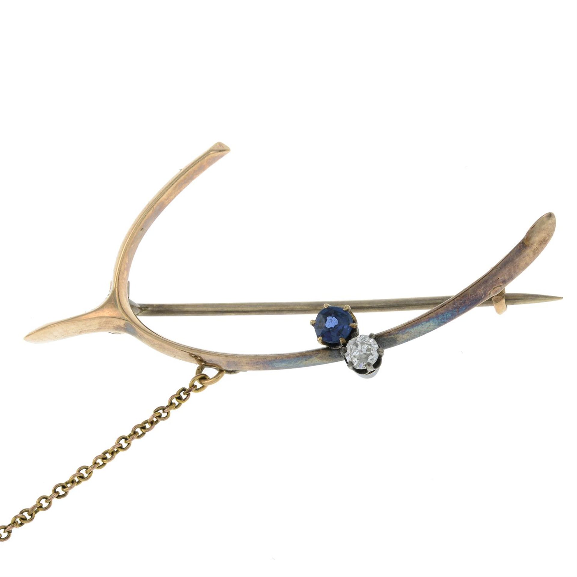 A wishing bone brooch, with sapphire and diamond accents.