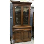 A Victorian mahogany floorstanding bookcase enclosed by a pair of glazed doors below a fluted