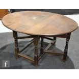 An 18th Century and later oak oval gate leg dining table on turned baluster legs united by rail