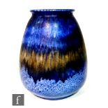 A large Ruskin Pottery barrel vase decorated in a dark blue dribble glaze with bands of glaze with a