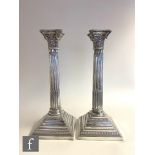 A pair of hallmarked silver Corinthian column candlesticks, stepped bases below acanthus capped