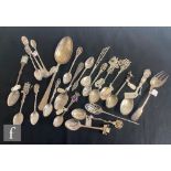 A collection of assorted silver and white metal spoons to include an example with soldiers aiming at