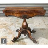 An early Victorian rosewood veneered fold-over tea table of serpentine outline, raised to an