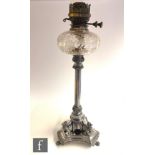 A late 19th Century silver plated oil lamp, the tricorn base raised on three claw feet supporting