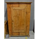 A 19th Century stripped pine cupboard, the hanging space enclosed by a panelled door below a moulded