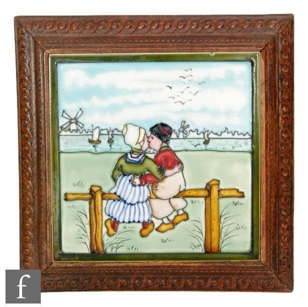 A framed 8in tile decorated with a tubelined Dutch scene with a lady and gentleman kissing whilst - Image 2 of 2