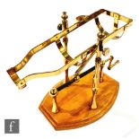 A brass port/wine decanting pourer, the frame with a wind out mechanism, raised on an wooden