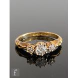 An 18ct hallmarked diamond three stone ring, old cut claw set stones to scroll detailed shoulders,