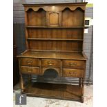 A 17th Century style oak dresser, the cupboard rack over a base fitted with five short drawers, on