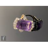 An 18ct hallmarked amethyst and diamond ring, central emerald cut amethyst set with five diamonds to