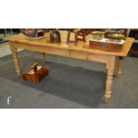 A Victorian large stripped pine farmhouse table, the plank top over a plain frieze on turned legs
