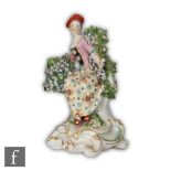 A late 18th to early 19th Century Chelsea Derby figure of a lady sat before a floral bocage on a