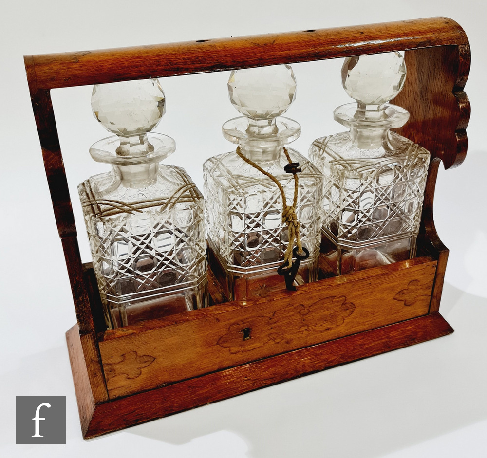 An Edwardian oak cased three bottle tantalus, width 35cm, lacking carrying handle.