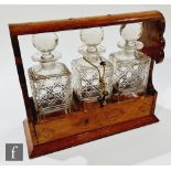 An Edwardian oak cased three bottle tantalus, width 35cm, lacking carrying handle.