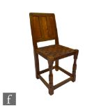 An oak side chair with triple fielded panel back over a woven leather strapwork seat and octagonal